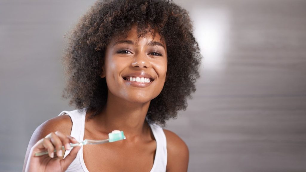 woman smiling and holding a toothbrush