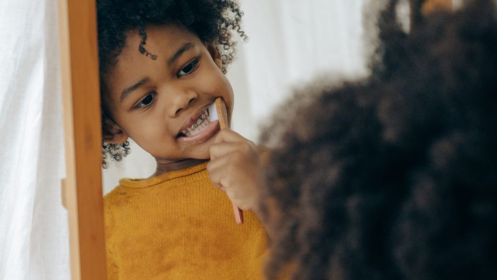 Child smiling while brushing teeth at home